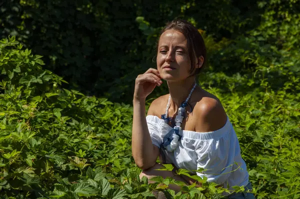 Bitkisel ilaçlar. Rahatlama inzivası. İnci kolyeli genç İspanyol kız, yeşil beyaz. Doğa terapisi. Yeşillik ormanında oturan bir kadın. Egzotik orman. Tropik güzellik. Sağlıklı cilt.