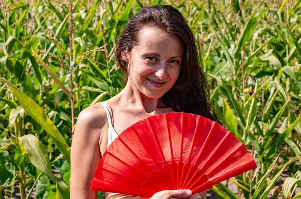 Gülümseyen yüzlü mutlu kadın kırmızı flamenko yaz hayranı sıcak mısır tarlasında, geyşa modasında.