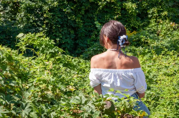 Yeşillik ormanında oturan bir kadın. Organik giysiler. Kırsal yaşam tarzı. Doğa inziva hayatı. Meditasyon köşesi ve sağlık. Çekici İspanyol kız, yeşil beyaz. Doğal güzellik. Boşluğu kopyala.