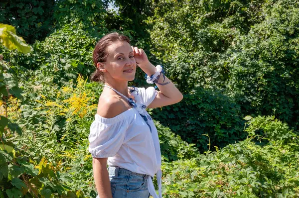 Yeşillik ormanında duran bir kadın. Organik giysiler. Kırsal yaşam tarzı. Doğa inziva hayatı. Meditasyon köşesi ve sağlık. Çekici İspanyol kız, yeşil beyaz. Doğal güzellik..