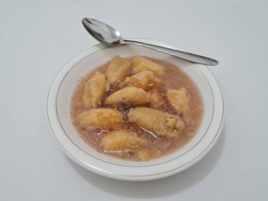 İçinde olgun muz dilimleri ve hindistan cevizi sütü sosu olan tatlı komposto.