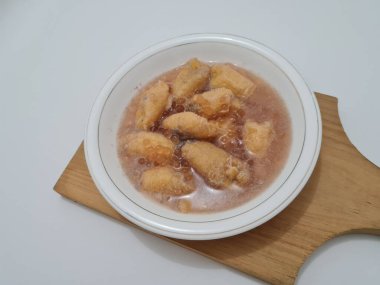 İçinde olgun muz dilimleri ve hindistan cevizi sütü sosu olan tatlı komposto.