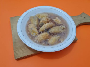 İçinde olgun muz dilimleri ve hindistan cevizi sütü sosu olan tatlı komposto.