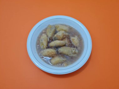 İçinde olgun muz dilimleri ve hindistan cevizi sütü sosu olan tatlı komposto.