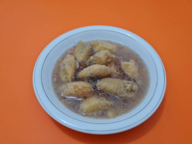 İçinde olgun muz dilimleri ve hindistan cevizi sütü sosu olan tatlı komposto.