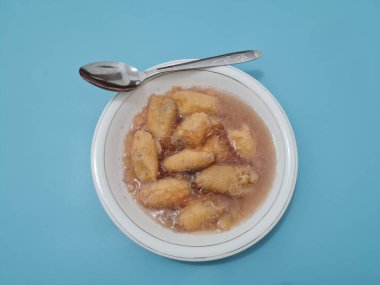 İçinde olgun muz dilimleri ve hindistan cevizi sütü sosu olan tatlı komposto.