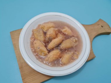 İçinde olgun muz dilimleri ve hindistan cevizi sütü sosu olan tatlı komposto.