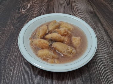 İçinde olgun muz dilimleri ve hindistan cevizi sütü sosu olan tatlı komposto.