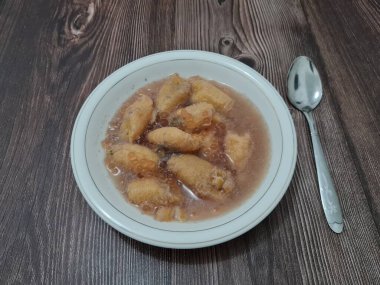 İçinde olgun muz dilimleri ve hindistan cevizi sütü sosu olan tatlı komposto.