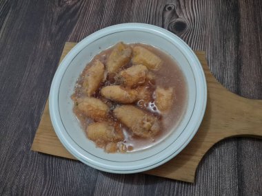 İçinde olgun muz dilimleri ve hindistan cevizi sütü sosu olan tatlı komposto.