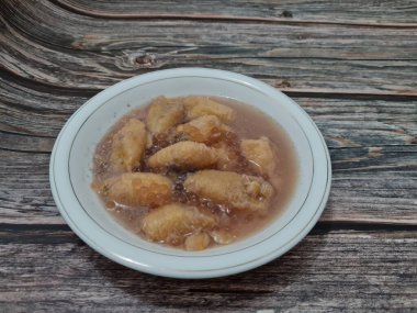 İçinde olgun muz dilimleri ve hindistan cevizi sütü sosu olan tatlı komposto.