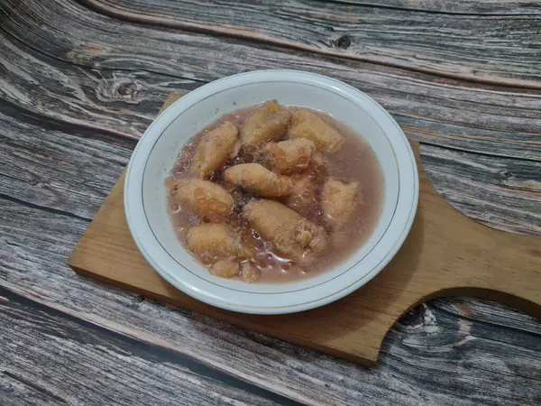 İçinde olgun muz dilimleri ve hindistan cevizi sütü sosu olan tatlı komposto.