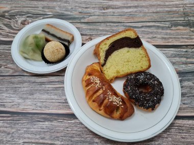 Sünger ekmeği, reçelli ekmek, çikolatalı çörek, Wingko, mendut atıştırmalıkları ve onde onde 'den oluşan bir pazar atıştırmalığı koleksiyonu.