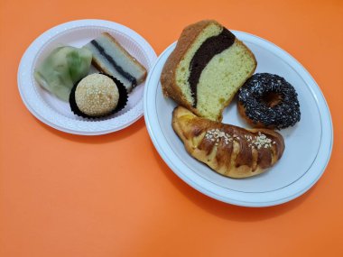 Sünger ekmeği, reçelli ekmek, çikolatalı çörek, Wingko, mendut atıştırmalıkları ve onde onde 'den oluşan bir pazar atıştırmalığı koleksiyonu.