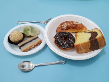 Sünger ekmeği, reçelli ekmek, çikolatalı çörek, Wingko, mendut atıştırmalıkları ve onde onde 'den oluşan bir pazar atıştırmalığı koleksiyonu.