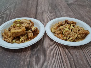 İçinde tempeh parçaları, tofu parçaları, lezzetli baharatlı fasulye filizleri olan bir çorba tabağı.