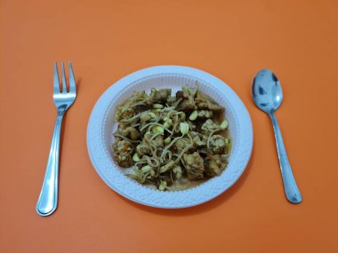 İçinde tempeh parçaları, tofu parçaları, lezzetli baharatlı fasulye filizleri olan bir çorba tabağı.