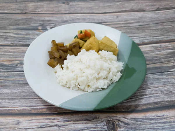 Mixed rice in a plate with side dishes of sliced fried tofu and delicious seasoned beef