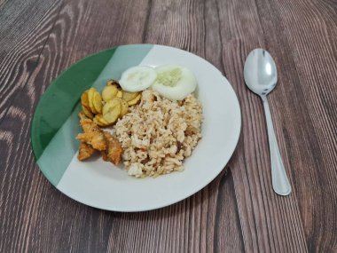 Kızarmış balık ve salatalık dilimli bir tabakta leziz pilav.