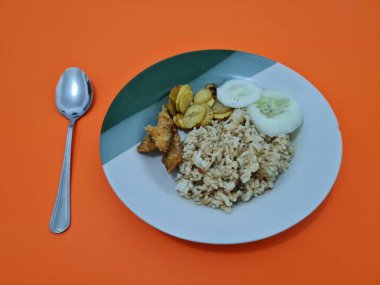 Kızarmış balık ve salatalık dilimli bir tabakta leziz pilav.