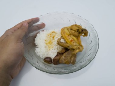 Yemek, içinde beyaz pirinç bulunan cam bir kasenin içinde. İçinde tavuk ve baharatlı tavuk ciğeri var.