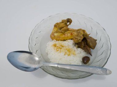 Yemek, içinde beyaz pirinç bulunan cam bir kasenin içinde. İçinde tavuk ve baharatlı tavuk ciğeri var.