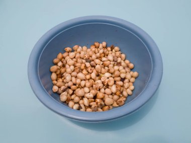 Mavi bir kabın içindeki deriden soyulmuş fıstıklar.