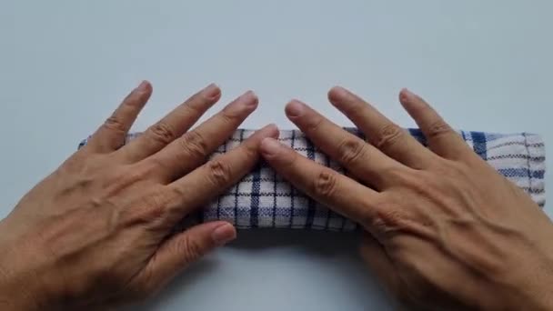 一个年轻人的手在折叠一张格子布餐巾时的动作 — 图库视频影像