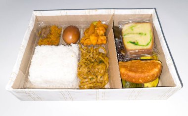 Kutudaki tipik Endonezya yemekleri arasında dilimlenmiş et, kızarmış erişte, pasta, sünger keki, kusmuk ve diğer şeyler vardır..