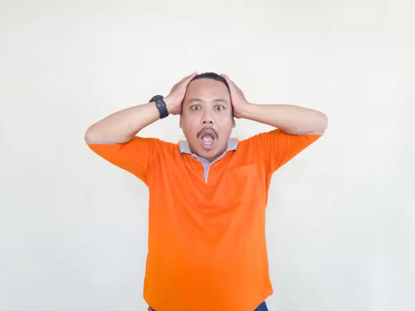 Asian adult male in orange t-shirt making gestures and facial expressions on white background