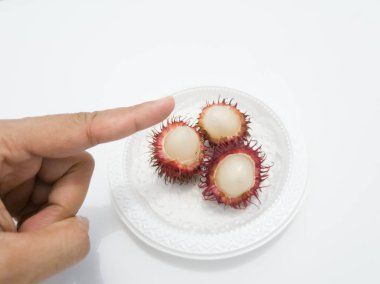 Beyaz arka planda beyaz bir plaka üzerinde Rambutan.