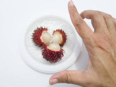 Beyaz arka planda beyaz bir plaka üzerinde Rambutan.