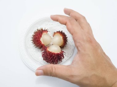 Beyaz arka planda beyaz bir plaka üzerinde Rambutan.