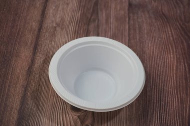 Ahşap bir arka planda plastikten yapılmış beyaz plastik bir tabak.