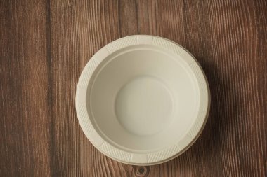 Ahşap bir arka planda plastikten yapılmış beyaz plastik bir tabak.
