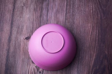 Ahşap arka planda pembe plastik kase