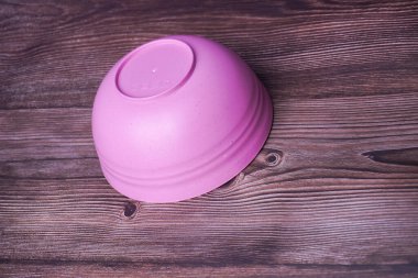 Ahşap arka planda pembe plastik kase