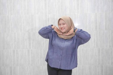 Endonezyalı Asyalı kadın tesettür ve mavi gömlek giyiyor.