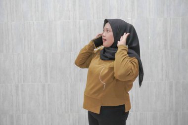 Kahverengi tesettürlü bir kadının mutlu ifadesi.