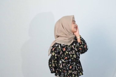 Asyalı Endonezyalı bir kadının tesettürlü, çiçekli siyah bir elbise giymesinin mutlu ifadesi.