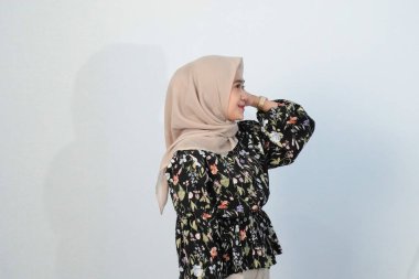 Asyalı Endonezyalı bir kadının tesettürlü, çiçekli siyah bir elbise giymesinin mutlu ifadesi.