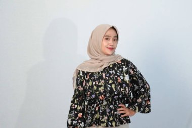 Asyalı Endonezyalı bir kadının tesettürlü, çiçekli siyah bir elbise giymesinin mutlu ifadesi.