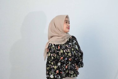 Asyalı Endonezyalı bir kadının tesettürlü, çiçekli siyah bir elbise giymesinin mutlu ifadesi.