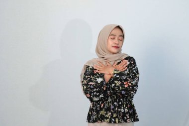 Asyalı Endonezyalı bir kadının tesettürlü, çiçekli siyah bir elbise giymesinin mutlu ifadesi.