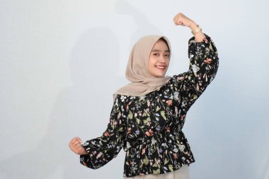 Asyalı Endonezyalı bir kadının tesettürlü, çiçekli siyah bir elbise giymesinin mutlu ifadesi.