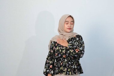Asyalı Endonezyalı bir kadının tesettürlü, çiçekli siyah bir elbise giymesinin mutlu ifadesi.