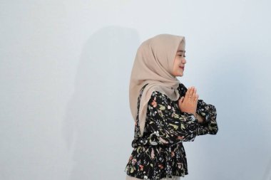 Asyalı Endonezyalı bir kadının tesettürlü, çiçekli siyah bir elbise giymesinin mutlu ifadesi.