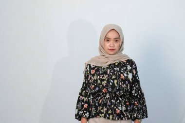 Asyalı Endonezyalı bir kadının tesettürlü, çiçekli siyah bir elbise giymesinin mutlu ifadesi.