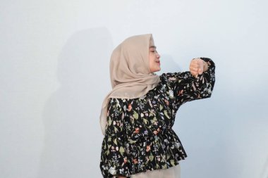 Asyalı Endonezyalı bir kadının tesettürlü, çiçekli siyah bir elbise giymesinin mutlu ifadesi.