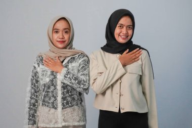 Açık mavi arka planda başörtüsü takan iki kız kardeşin ifadesi.